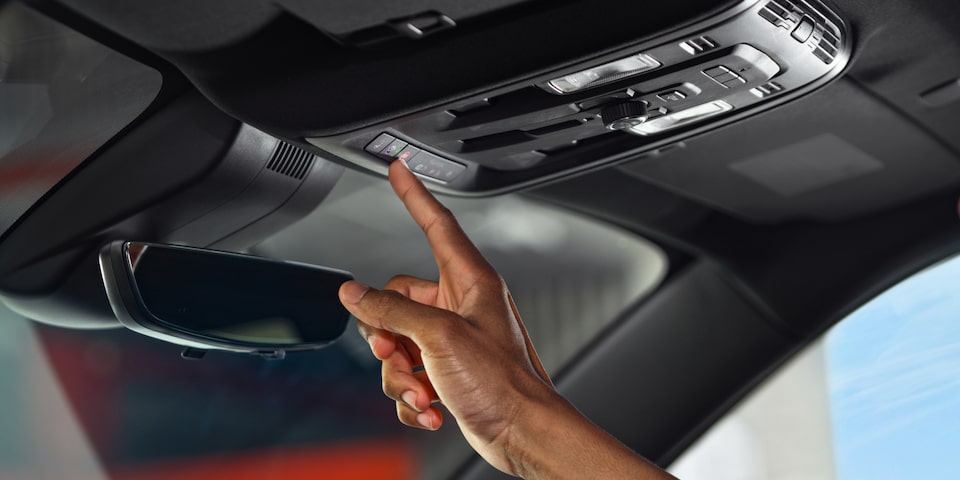 A person pressing a button inside the 2025 GMC Acadia Elevation.