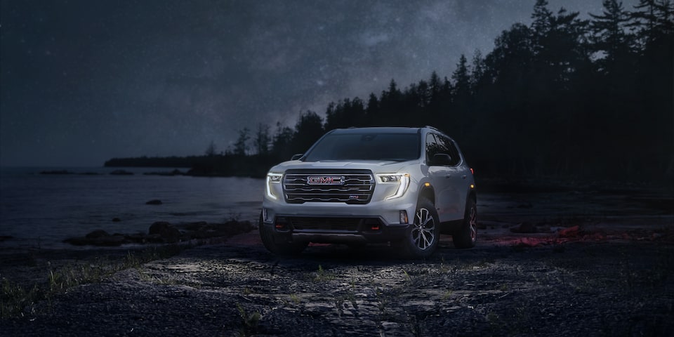 Front-side view of the 2025 GMC Acadia driving alone at night.