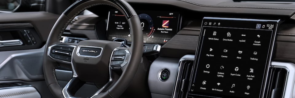 Close up view of the steering wheel and infotainment screen of the 2025 GMC Acadia.