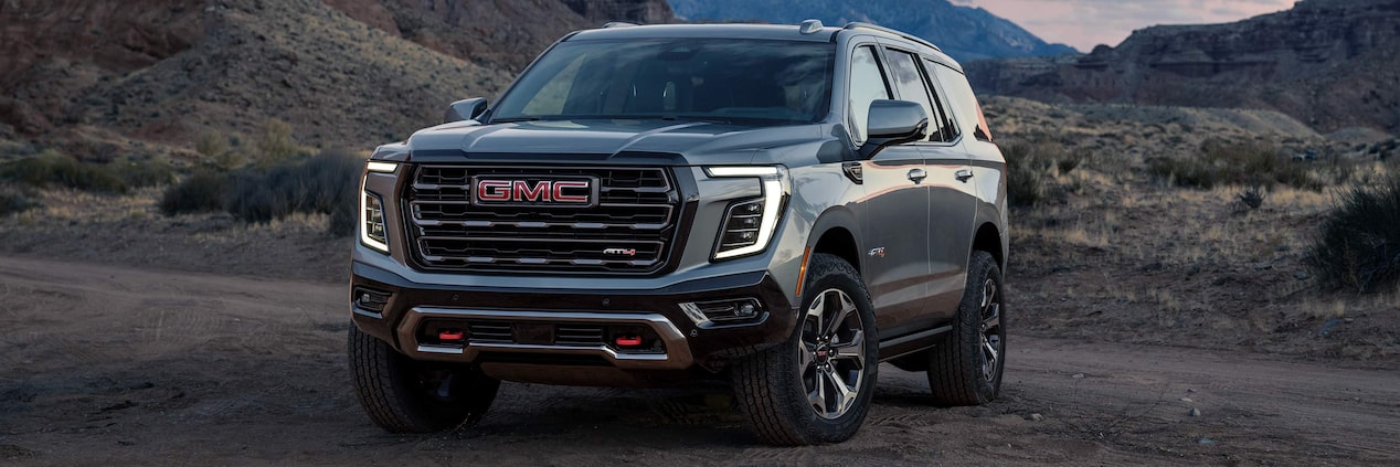 Front-side view of the 2025 GMC Yukon SUV parked in the desert at sunset.