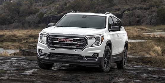 Front view of the 2024 GMC Terrain parked alone outdoors beside a pond.