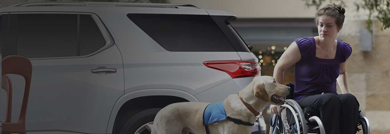 A person in a wheelchair beside a GM vehicle eligible for GM's Mobility Program.