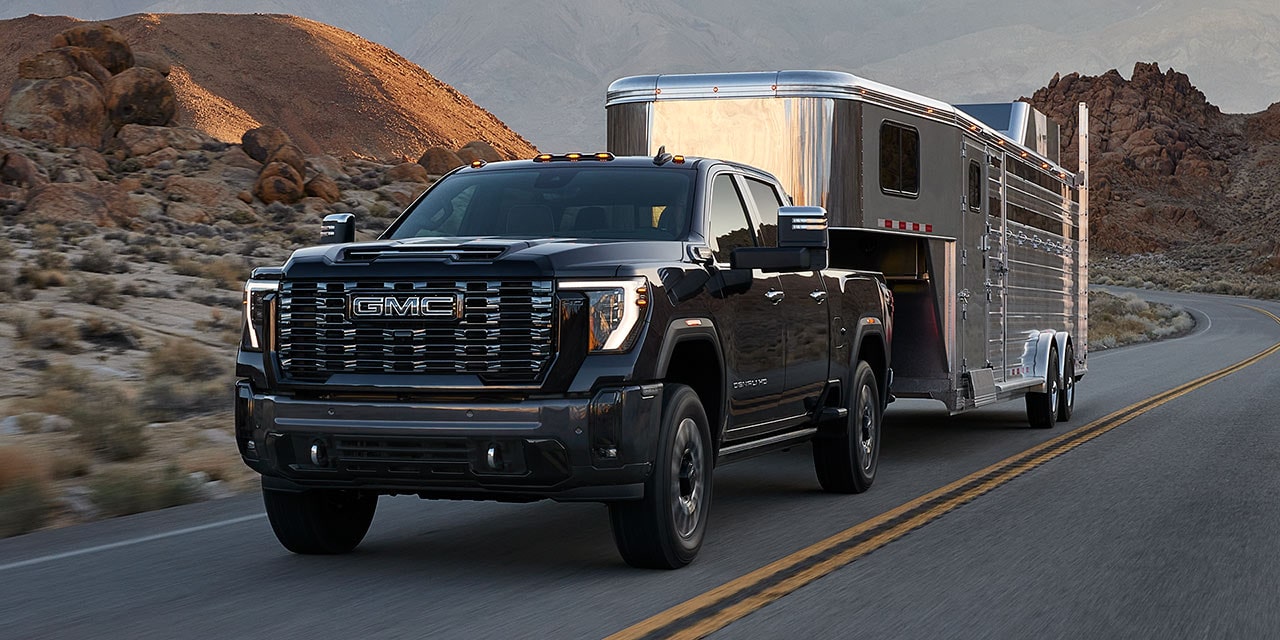 The GMC Sierra HD Pickup Truck towing a trailer on the road.