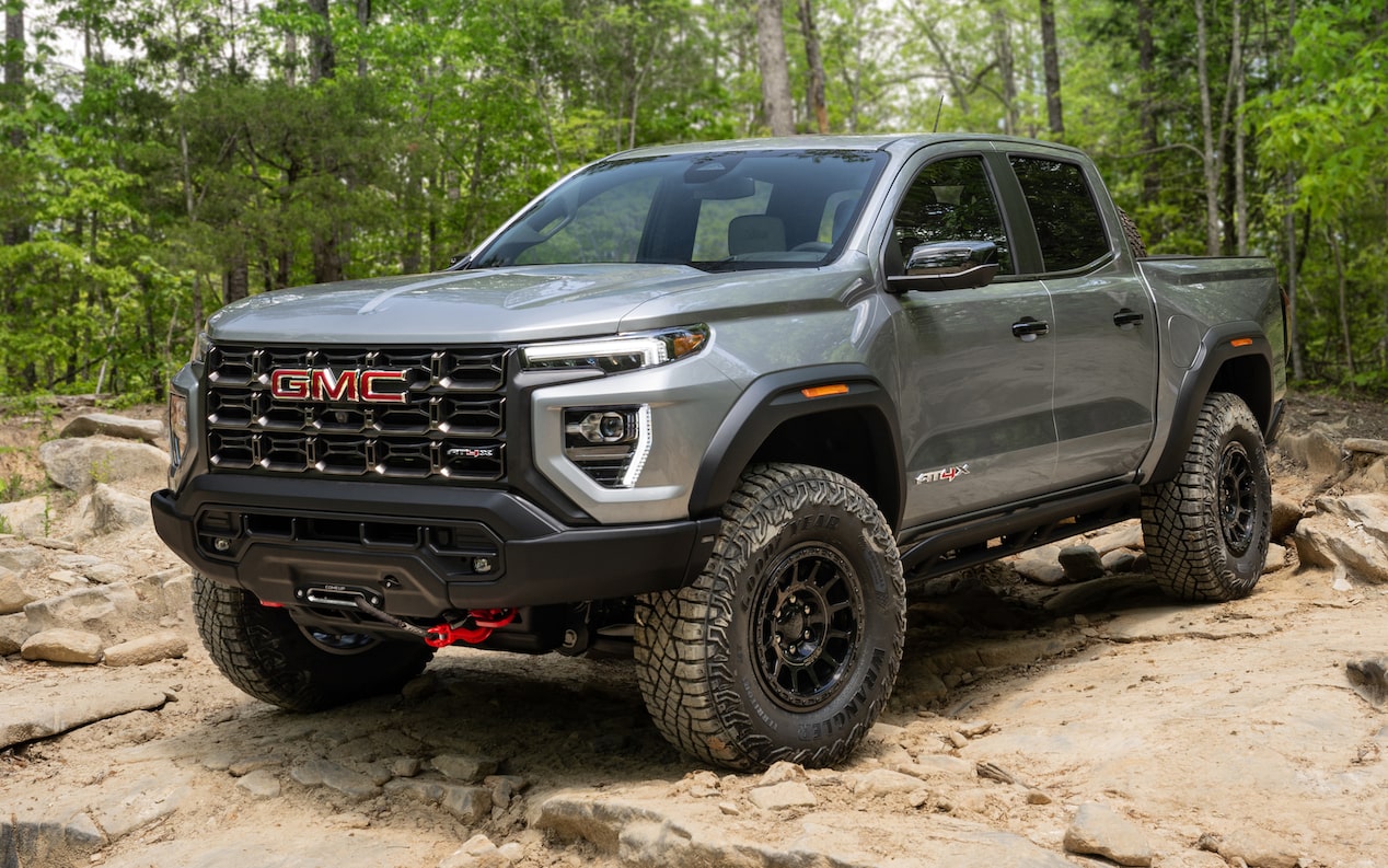 2024 GMC Canyon AT4X AEV parked in a tree-lined rocky terrain.