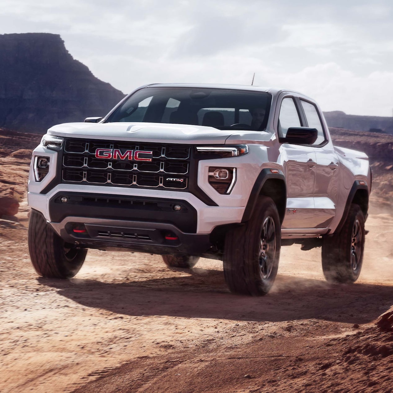 2024 GMC Canyon AT4 driving alone on a dusty road.