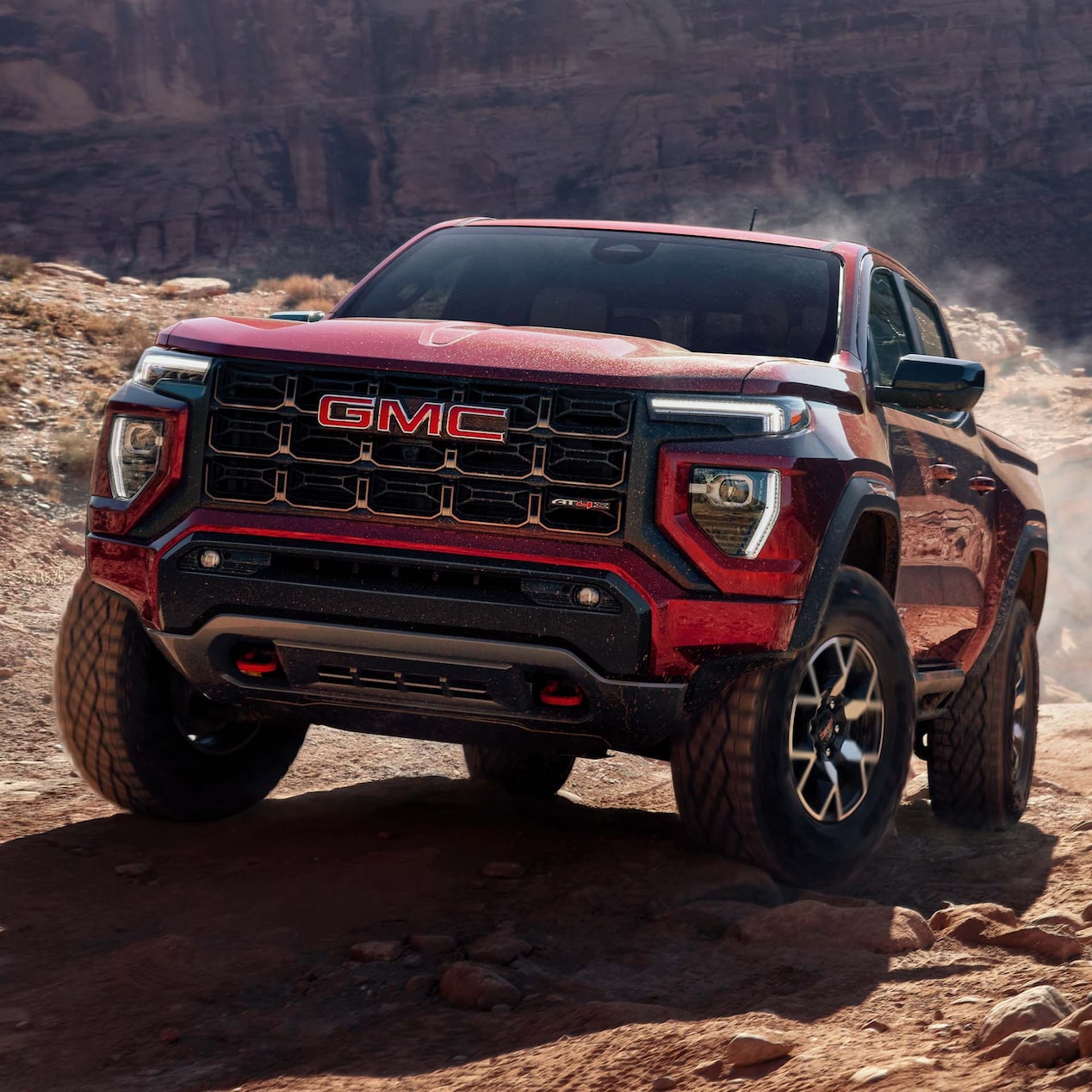 2024 GMC Canyon AT4X driving on a rugged terrain.