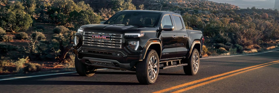 The 2025 GMC Canyon Denali driving alone on the road.