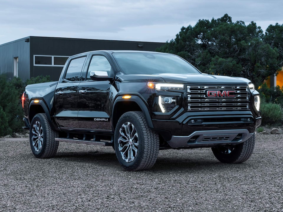 Front-side view of a 2025 GMC Canyon Denali parked with its Headlights on.