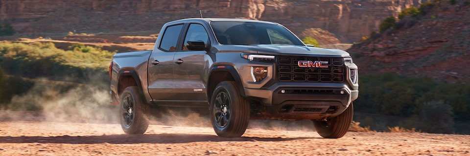 Front-side view of the 2025 GMC Canyon Pickup Truck parked on a dusty terrain.