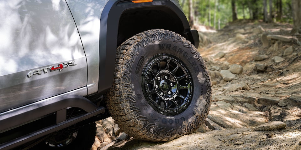 Close-up view of the 2025 GMC Canyon AT4 tires while off-roading on a rocky path.