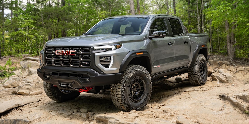 Front-side view of the 2025 GMC Canyon AT4X AEV Pickup Truck parked near trees.