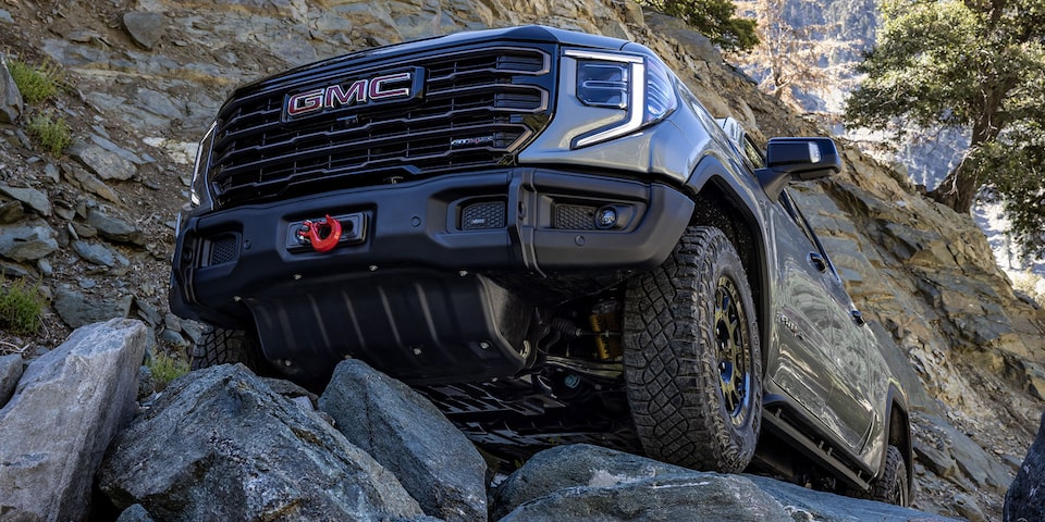 Camion GMC Sierra AT4 en mouvement sur un terrain accidenté.