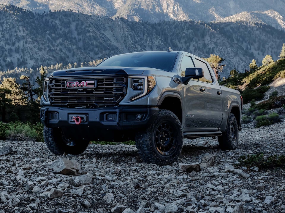 Vue latérale avant du camion GMC Sierra 1500 AT4 stationné sur un terrain rocailleux.