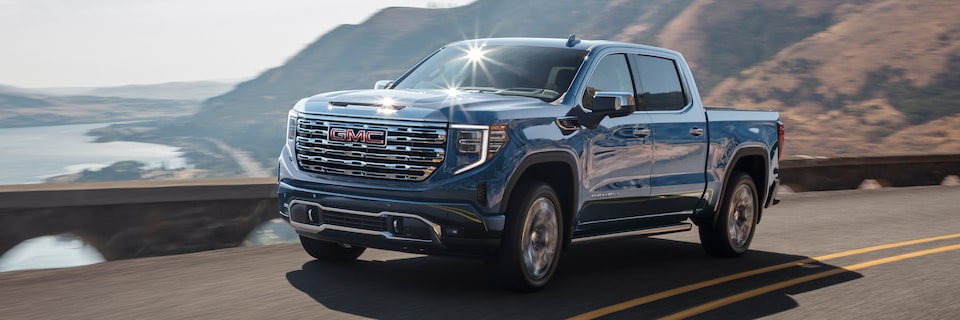 2025 GMC Sierra 1500 Driving Down a Winding Road with Mountains in the Background