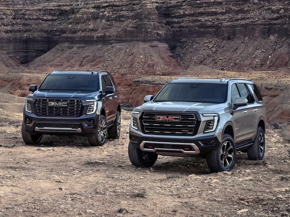 Two GMC Yukon Full-Size SUV's Parked Next to Each Other with Mountains in the Background