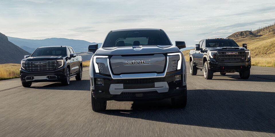 Three GMC Sierra Pickup Trucks Driving Down an Open Road