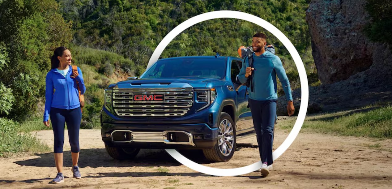 Two People Walking Away from Their GMC Sierra Truck with a Circle Shaped Graphic Surrounding the Truck