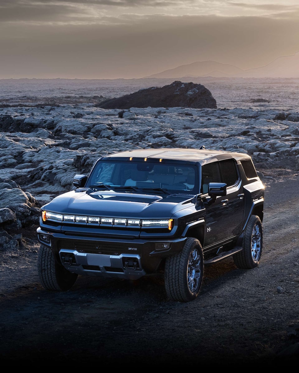 Wide Front Three-Quarters View of the 2025 GMC HUMMER EV SUV Driving on a Dirt Path