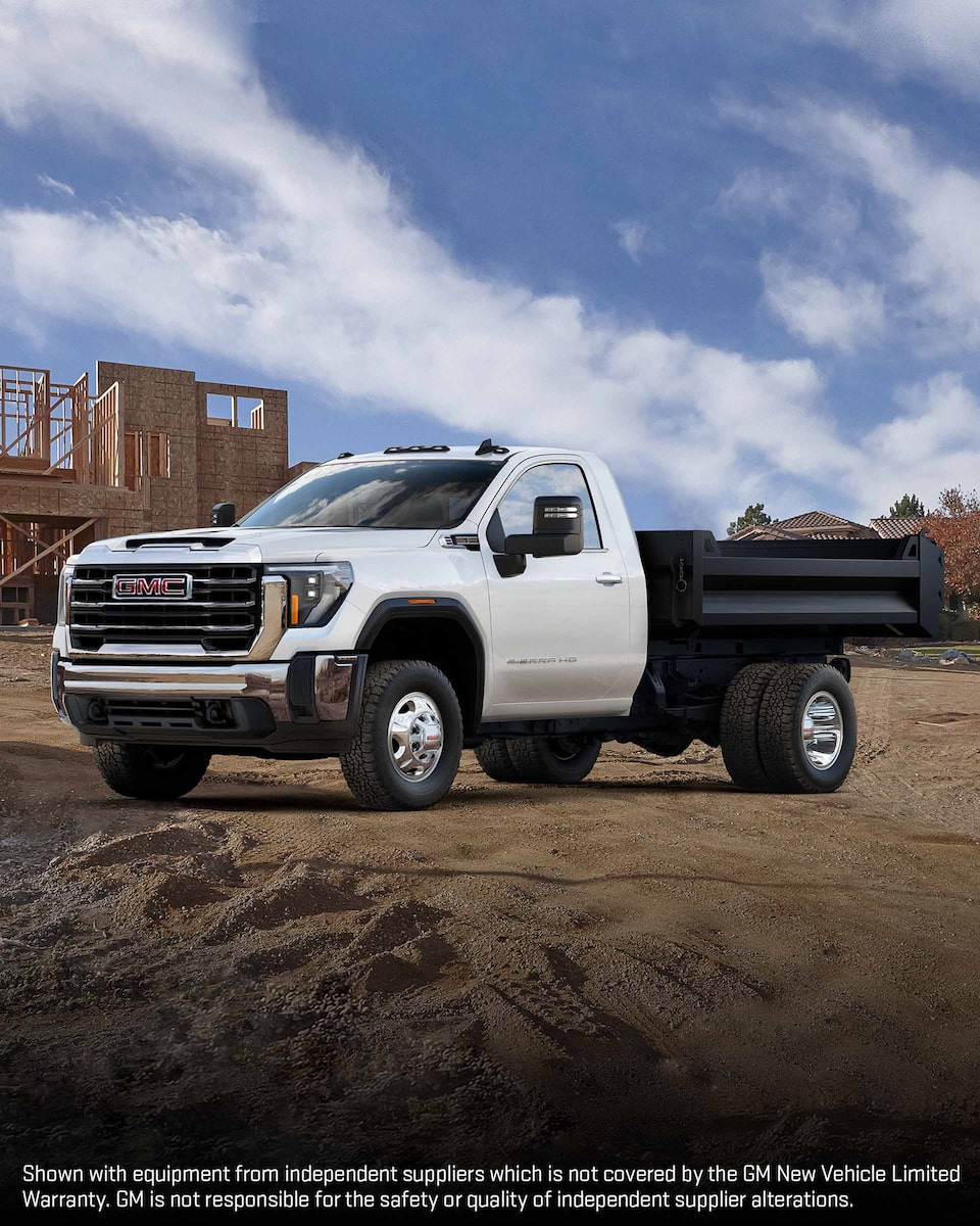 Wide Front Three-Quarters View of a 2024 GMC Sierra HD 3500 Chassis Cab Truck Parked In Front of a Worksite 