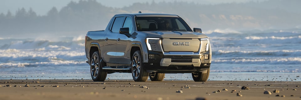 Front-side view of the 2025 GMC Sierra EV Denali parked by the beach.